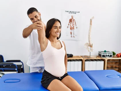 Practitioner assisting a seated patient with shoulder movement